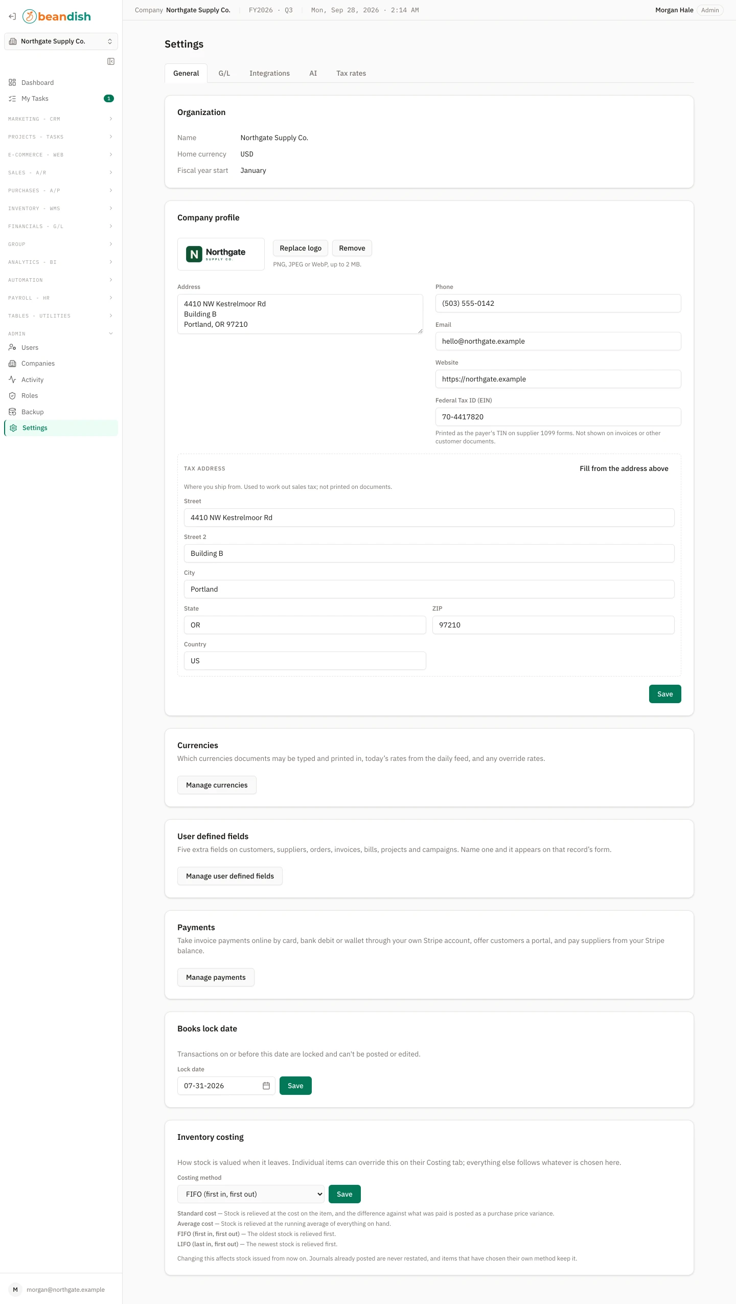 The company settings page on its General tab, with tabs for G/L, Integrations, AI and Tax rates: the organization’s name, home currency and fiscal year start; the company profile with its logo, address, phone, email, website and federal tax ID, and a tax address broken into street, city, state, ZIP and country; cards for currencies, user defined fields and payments; the books lock date; and the inventory costing method